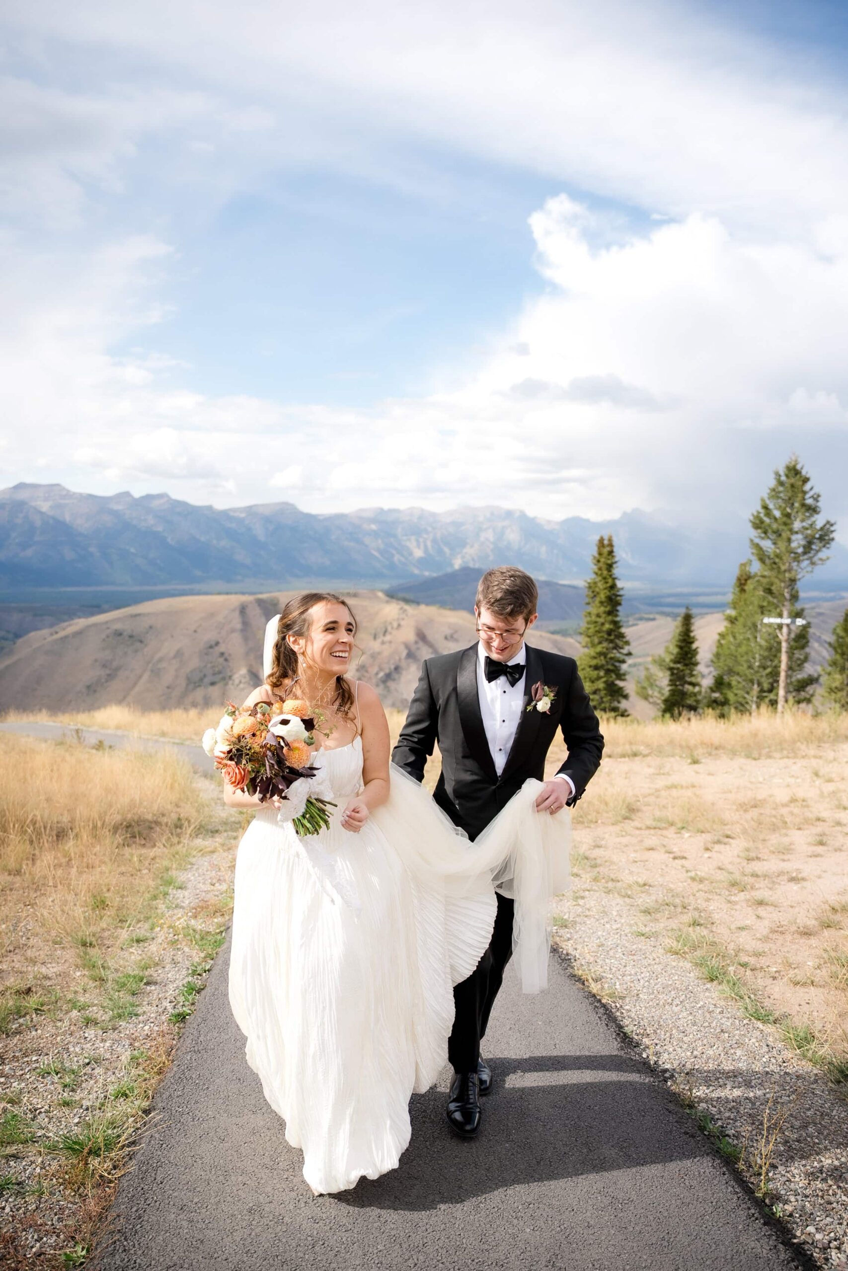 Bride and Groom walking on top of snow king mountain resort with teton views behind them