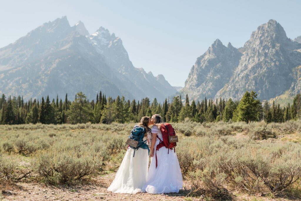 two brides kissing with grand tetons in the back