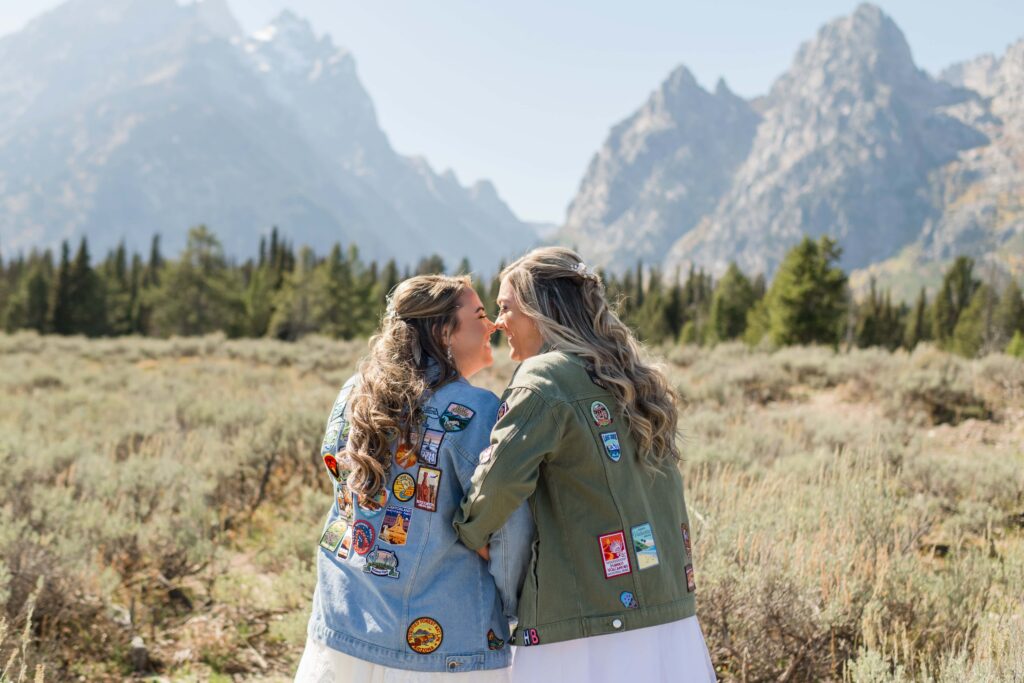 bride and bride touching noses with mountains in back