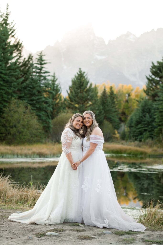 brides hold hands in front of grand tetons