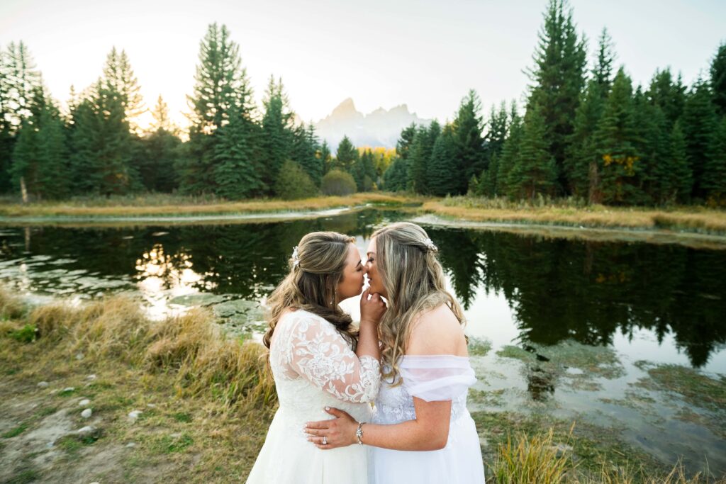 brides hold hands in front of grand tetons