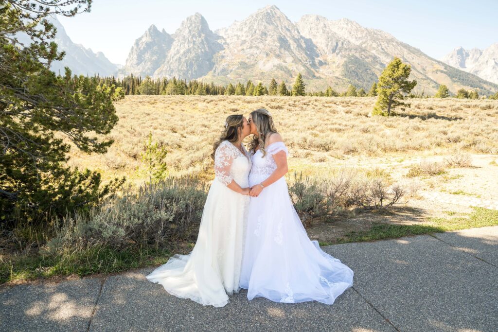 two brides kissing with grand tetons in the back