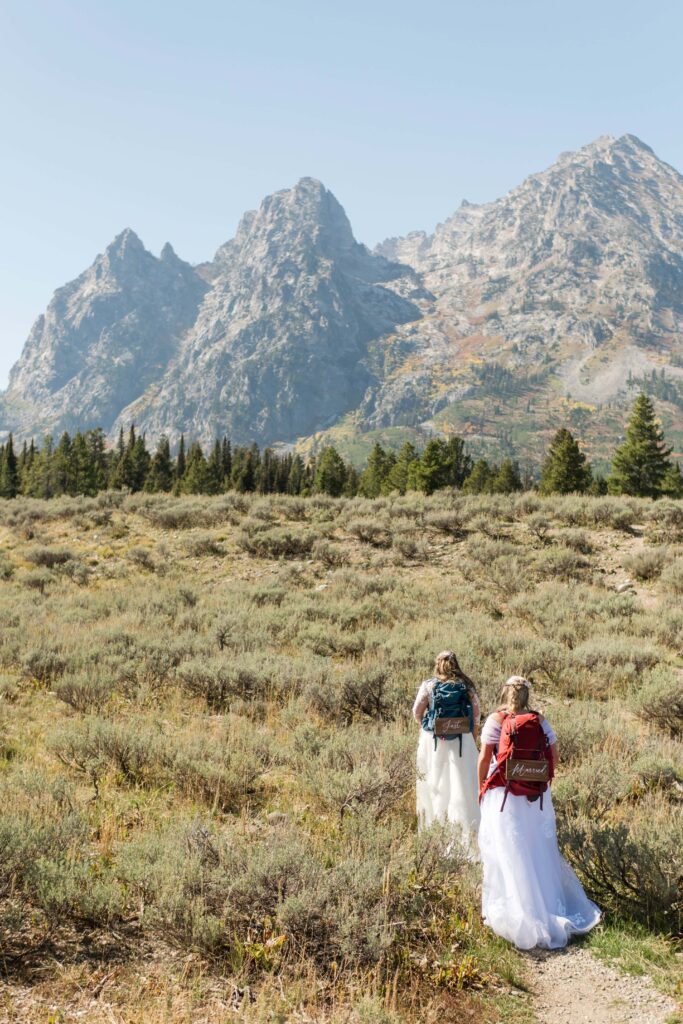 two brides hiking with grand tetons in the back