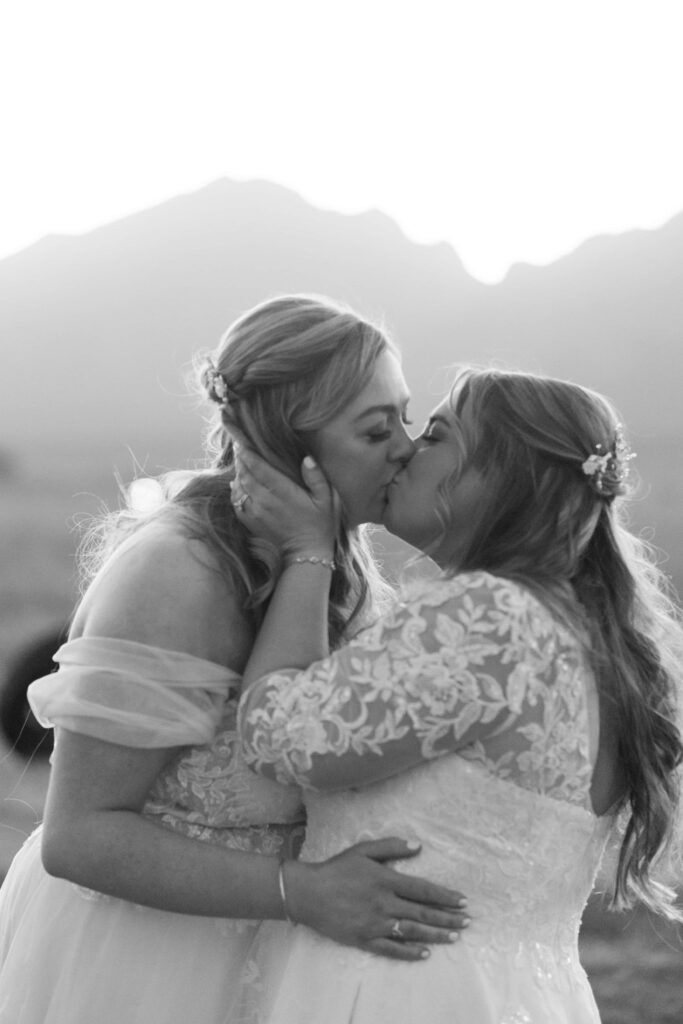 two brides kissing with tetons in back