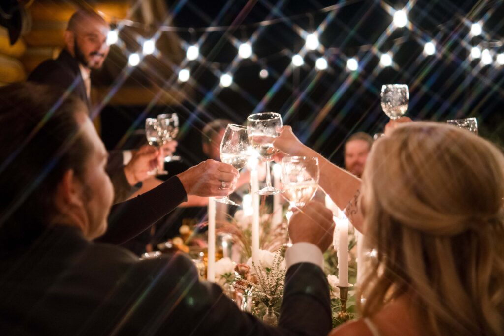 Jackson Hole wedding couple cheers drinks with their guests at dinner after their elopement in grand teton national park