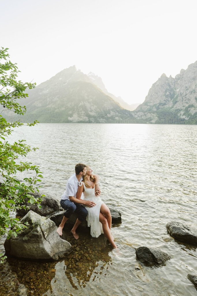 couple sitting on rocks enjoying the views at jenny lake in grand teton national park