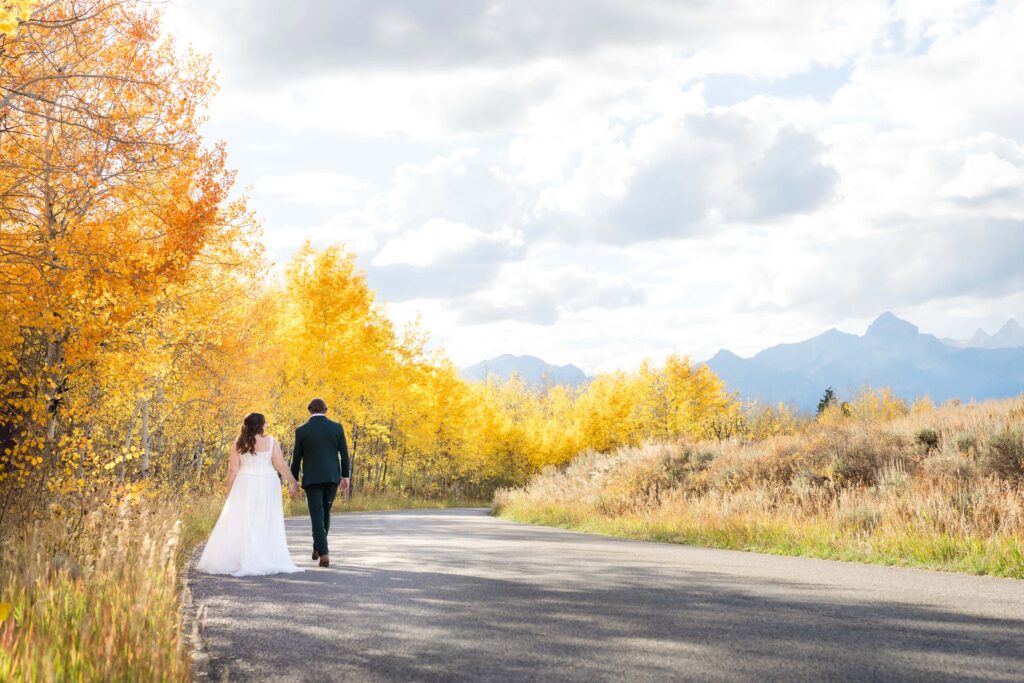 couple walks on their wedding day surrounded by fall foliage in grand teton national park