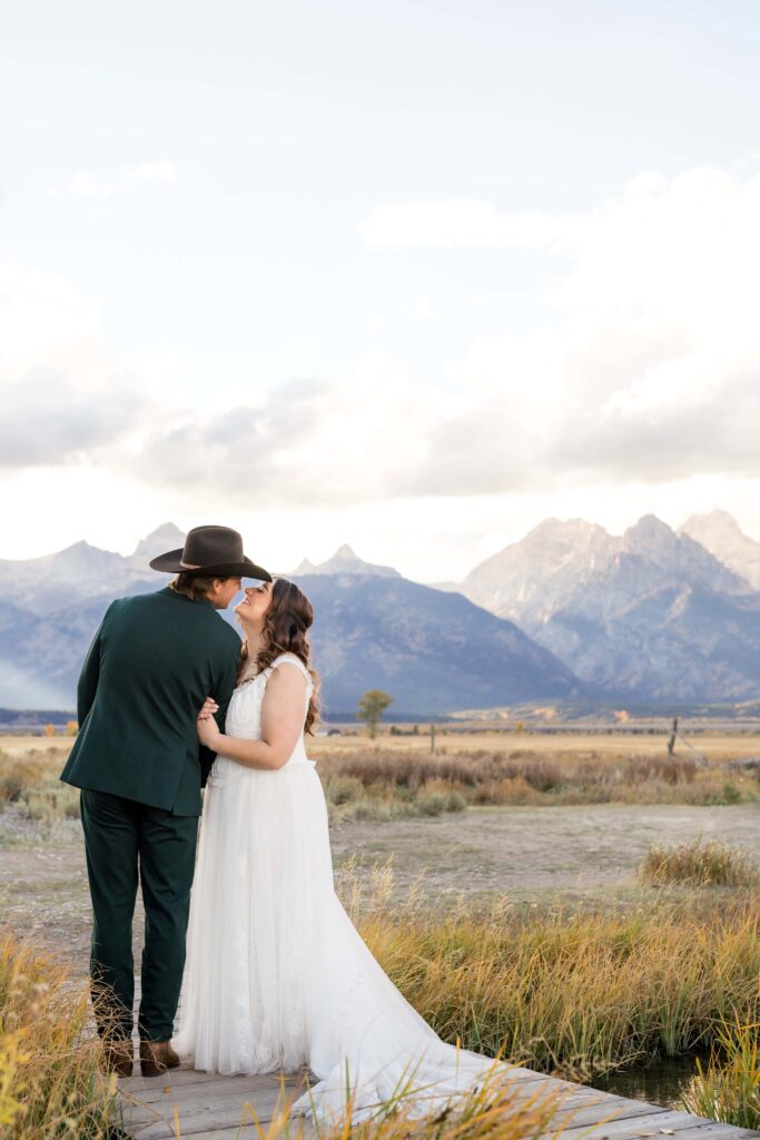 A couple shares a kiss on their wedding day with panoramic views of the Grand Teton mountain range.