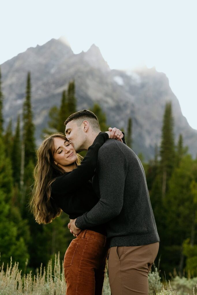 Couple kissing with grand teton peak in the background