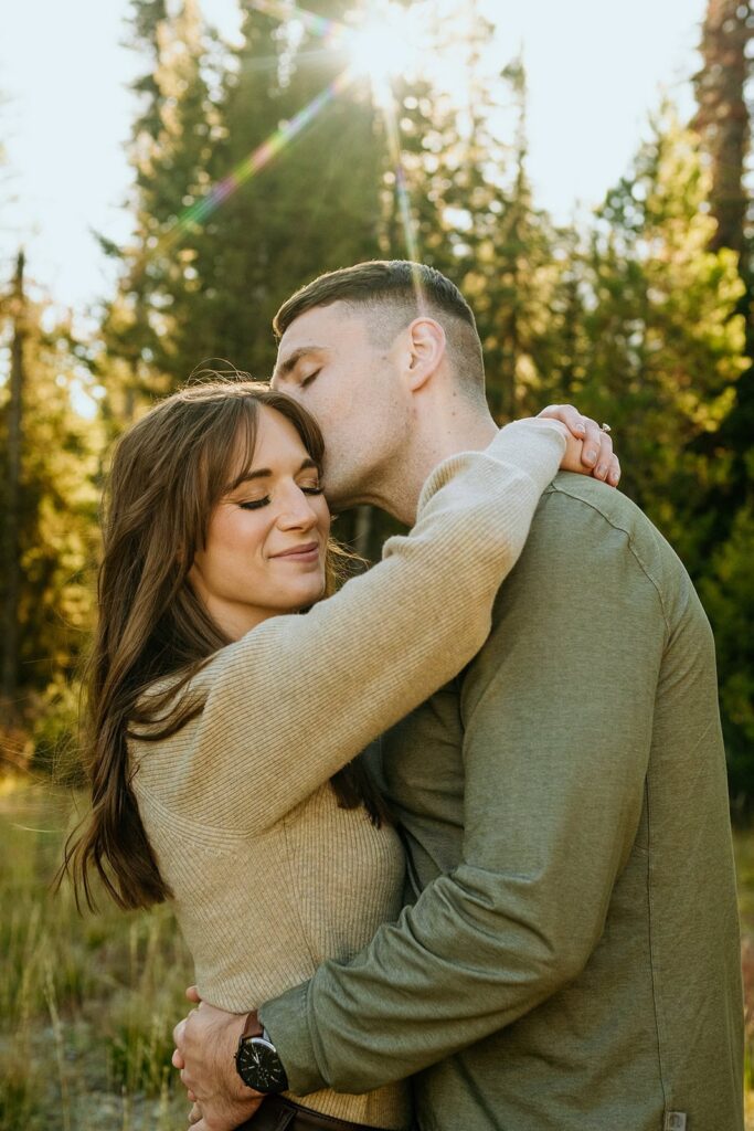 Couple kissing with light flare and trees in background