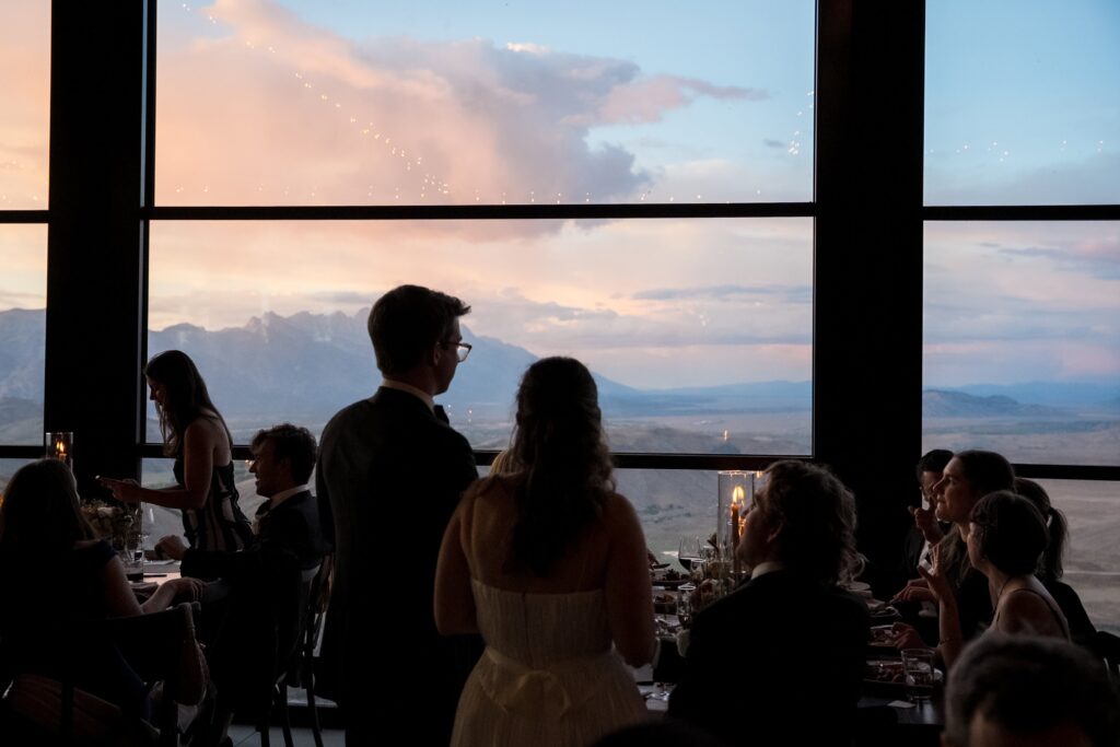 Bride and groom talking with guests with a colorful sunset overlooking the tetons