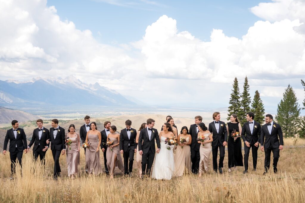 Bridal party walks with bride and groom on top of snow king mountain in jackson hole