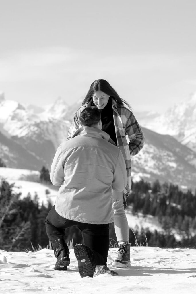 A man proposes to a woman in front of the grand teton mountains in the winter captured  in black and white by Karina Dopp - A jackson hole wedding photographer