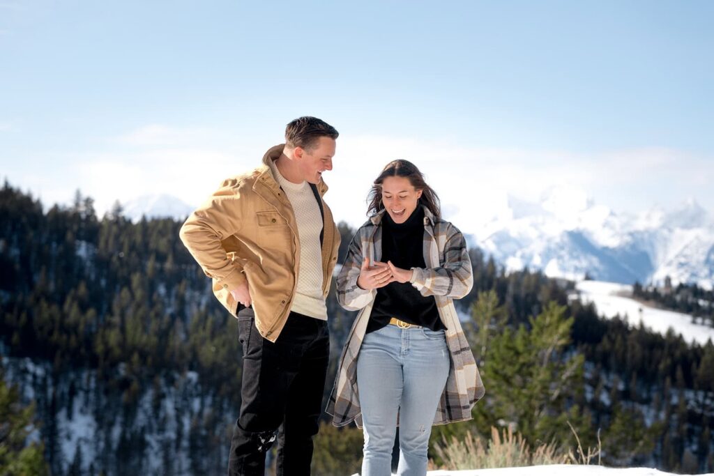 A man and woman are standing in the mountains in Jackson Hole, Wyoming after getting a winter proposal. 