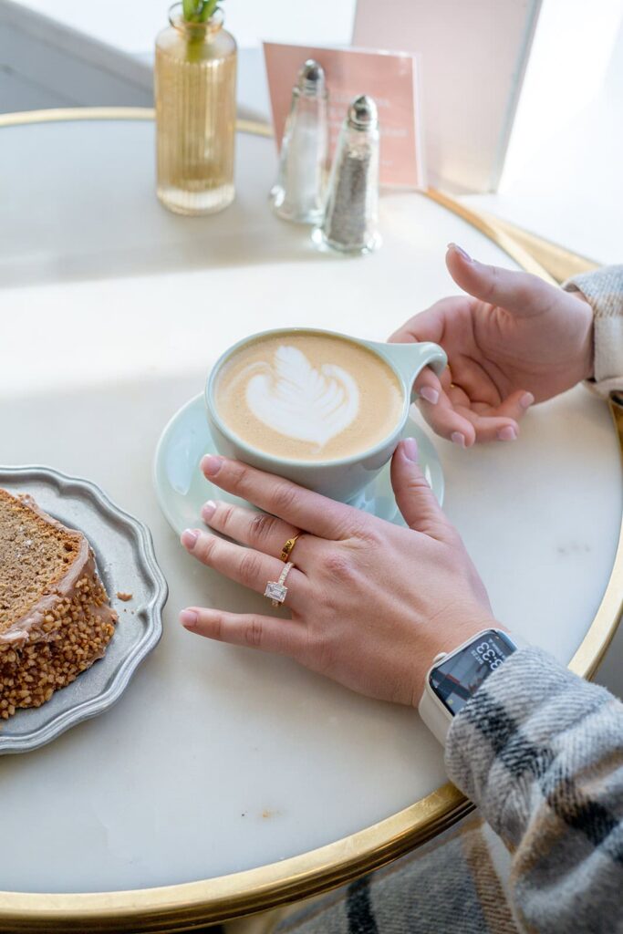 A woman's hands with a beautiful diamond engagement ring and a handcrafted latte made at Persephonie's Bakery in jackson wyoming